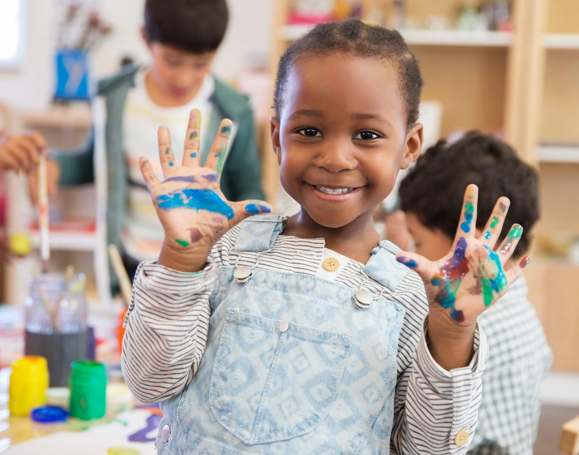 A child showing paint on their hands.