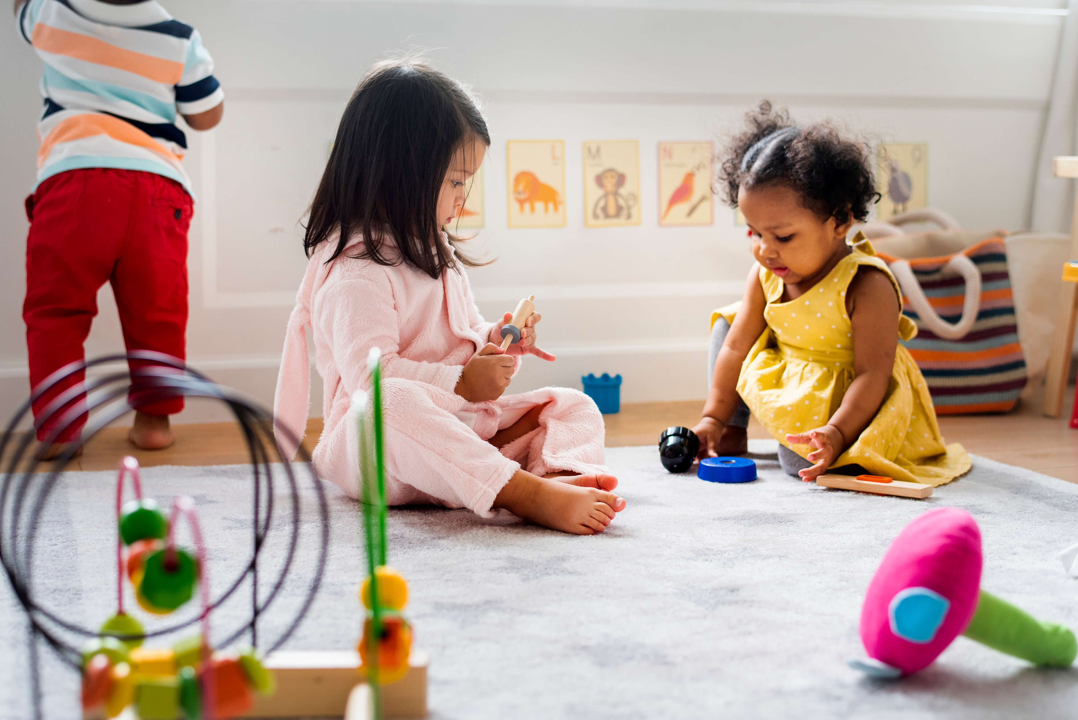 Two children sitting on the ground and playing with toys.