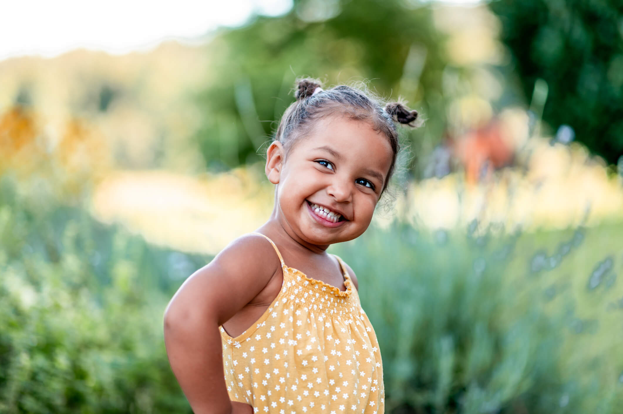 A smiling young standing in a field. 