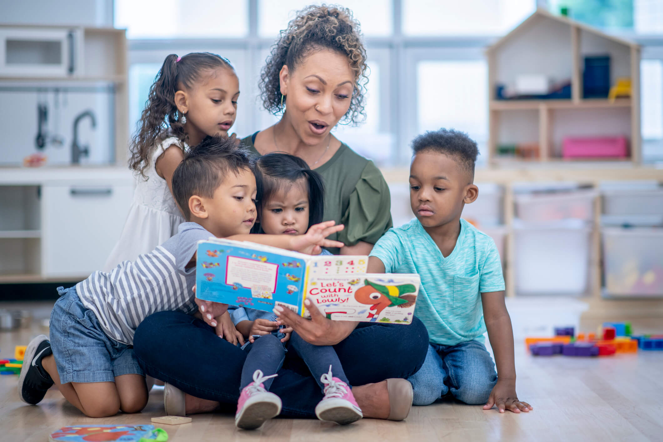 Teacher reading a book to a group of children.